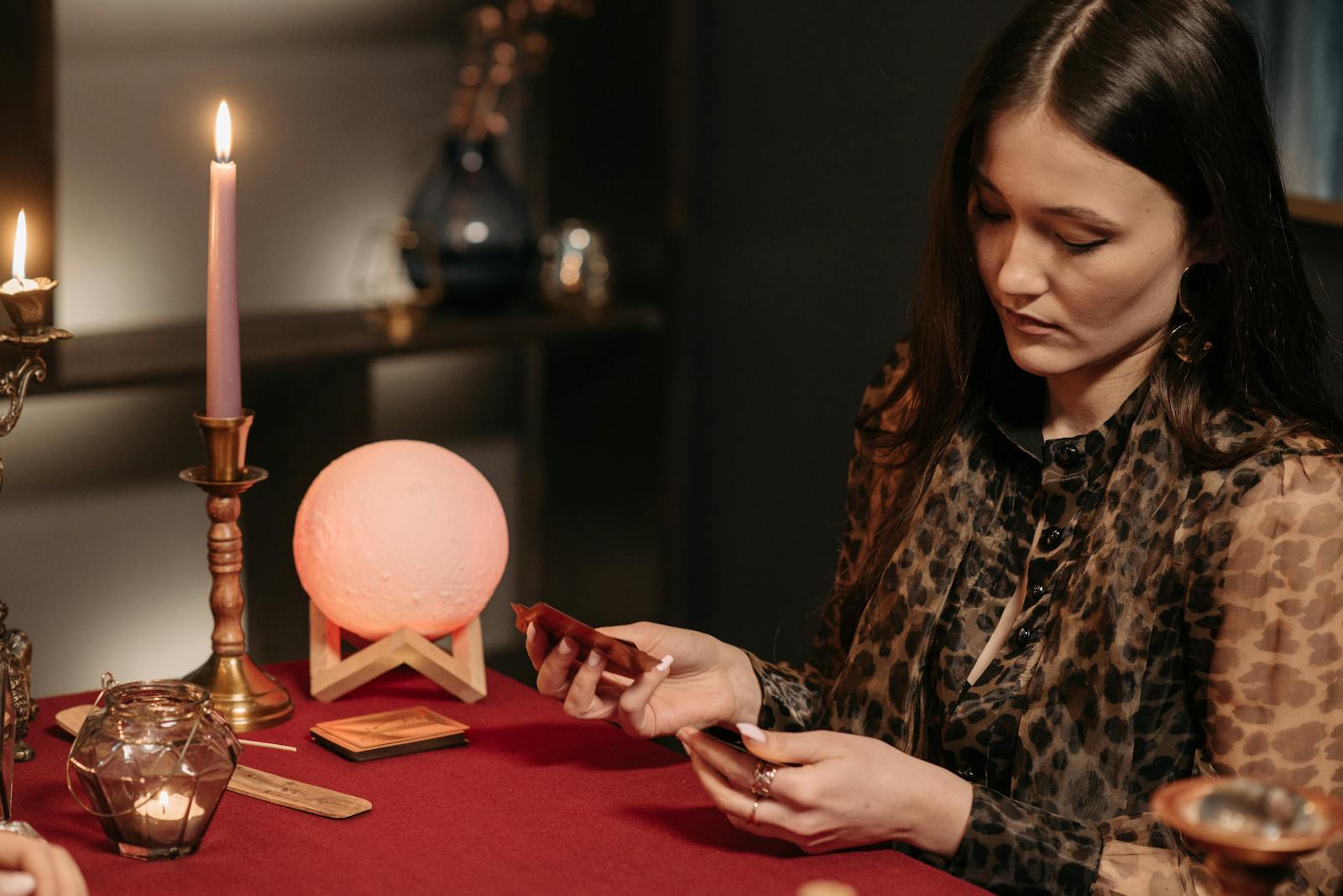 Woman engaged in fortune telling with tarot cards in a candlelit setting.