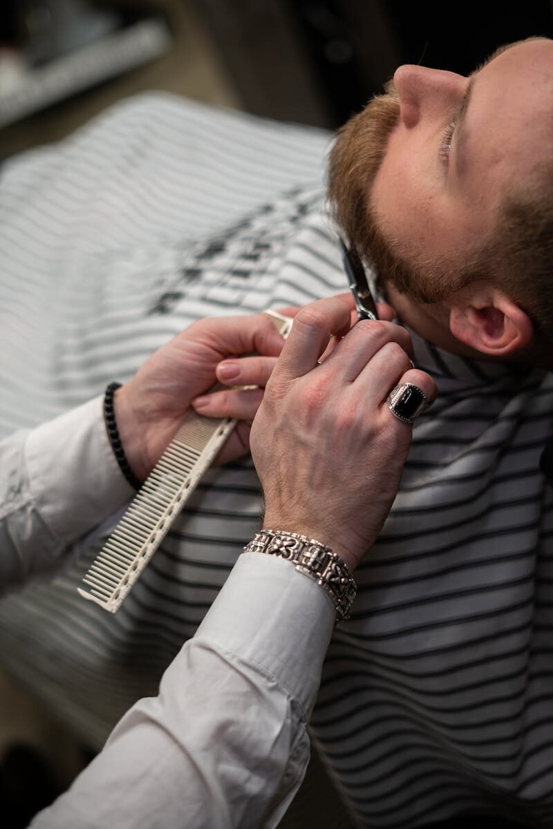 Barber carefully trims beard of client in a professional barbershop setting.